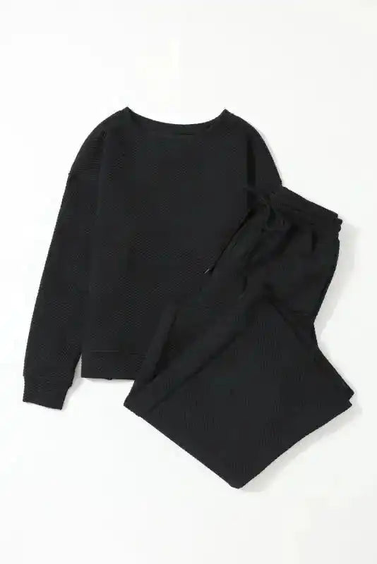 Flat lay of women's black textured loungewear set with slouchy fit, including ribbed long-sleeve top and wide-leg pants.