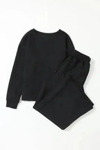 Flat lay of women's black textured loungewear set with slouchy fit, including ribbed long-sleeve top and wide-leg pants.