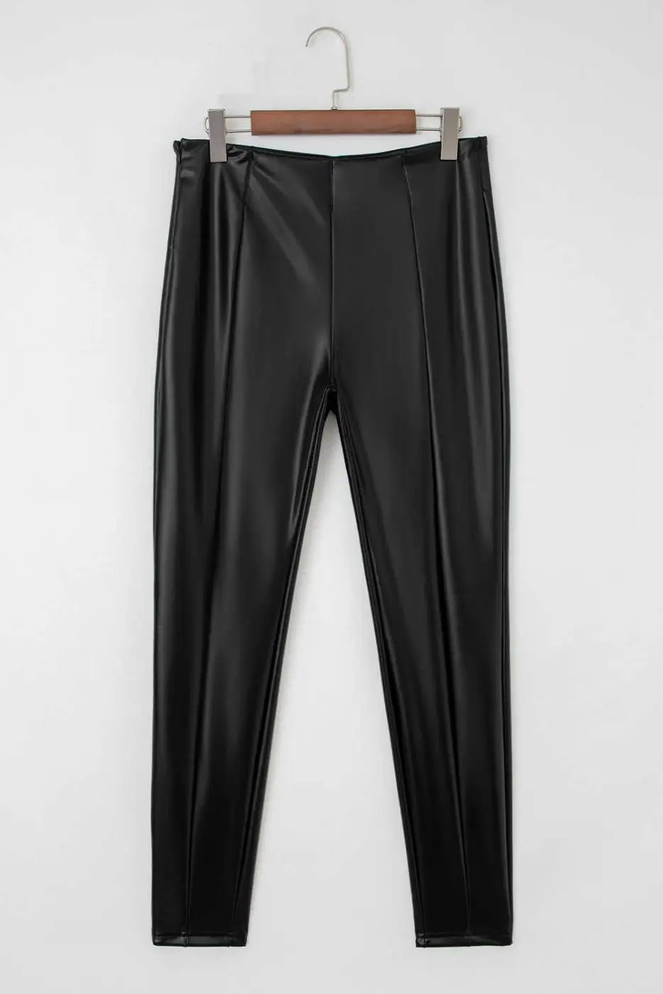 Flat lay of Black Vegan Leather Leggings – High‑Rise Skinny Fit showing front seam detailing and sleek faux leather texture.