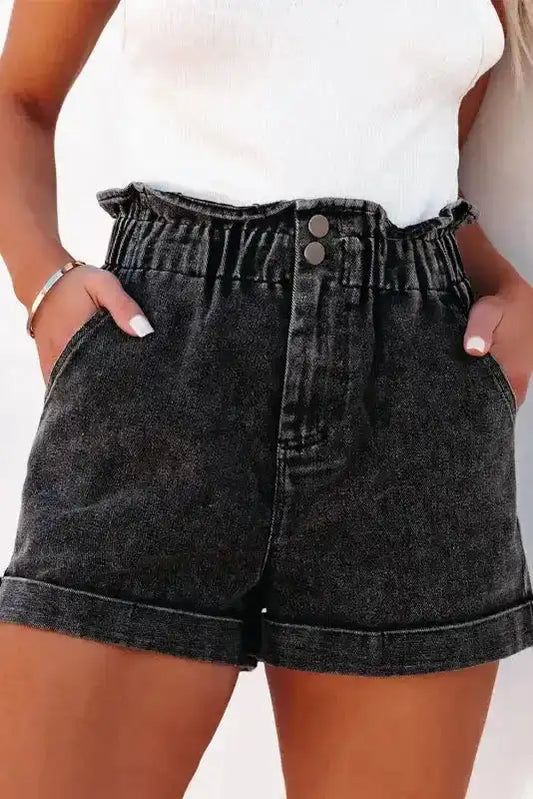 Ladies black vintage washed denim shorts with high waist and frilled hem, styled with front pockets and rolled cuffs for a casual look.