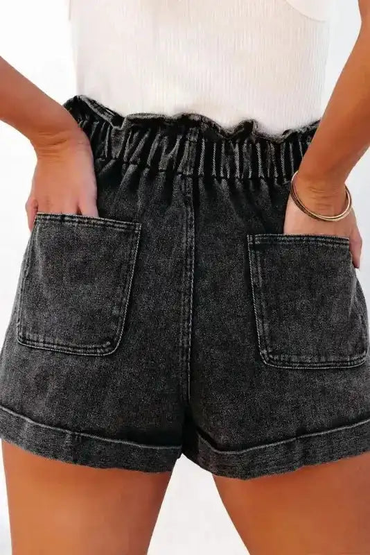 Back view of high waist black vintage washed denim shorts with frilled hem and two patch pockets, perfect for relaxed styling.