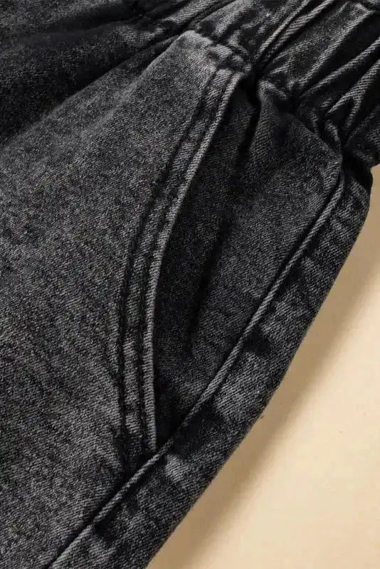 Detailed view of side pocket stitching on black vintage washed denim shorts, emphasizing texture and craftsmanship.