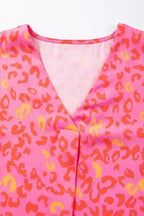 Close-up of V-neck detail on Wild in Pink Leopard Blouse. Lightweight fabric with vibrant pink and orange leopard print for a bold summer look.