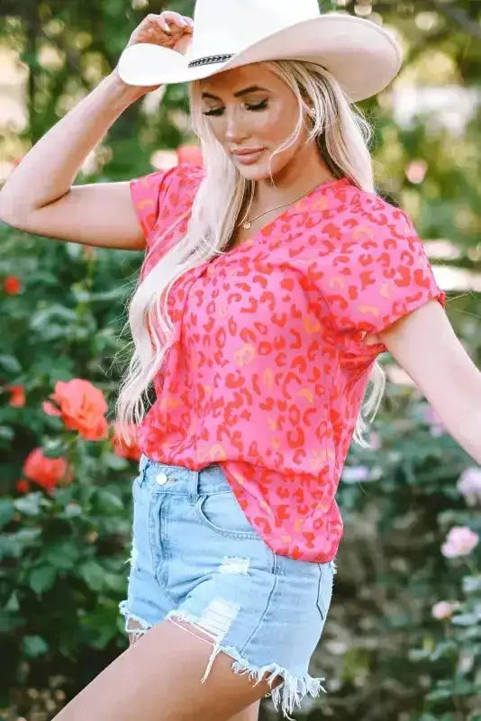 Wild in Pink V-neck leopard blouse styled with frayed denim shorts and a white cowboy hat. Feminine and bold summer top for casual occasions.