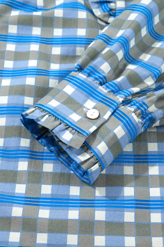 Detail of cuff on blue plaid long sleeve frilled blouse with button closure and subtle ruffle trim in soft cotton fabric.