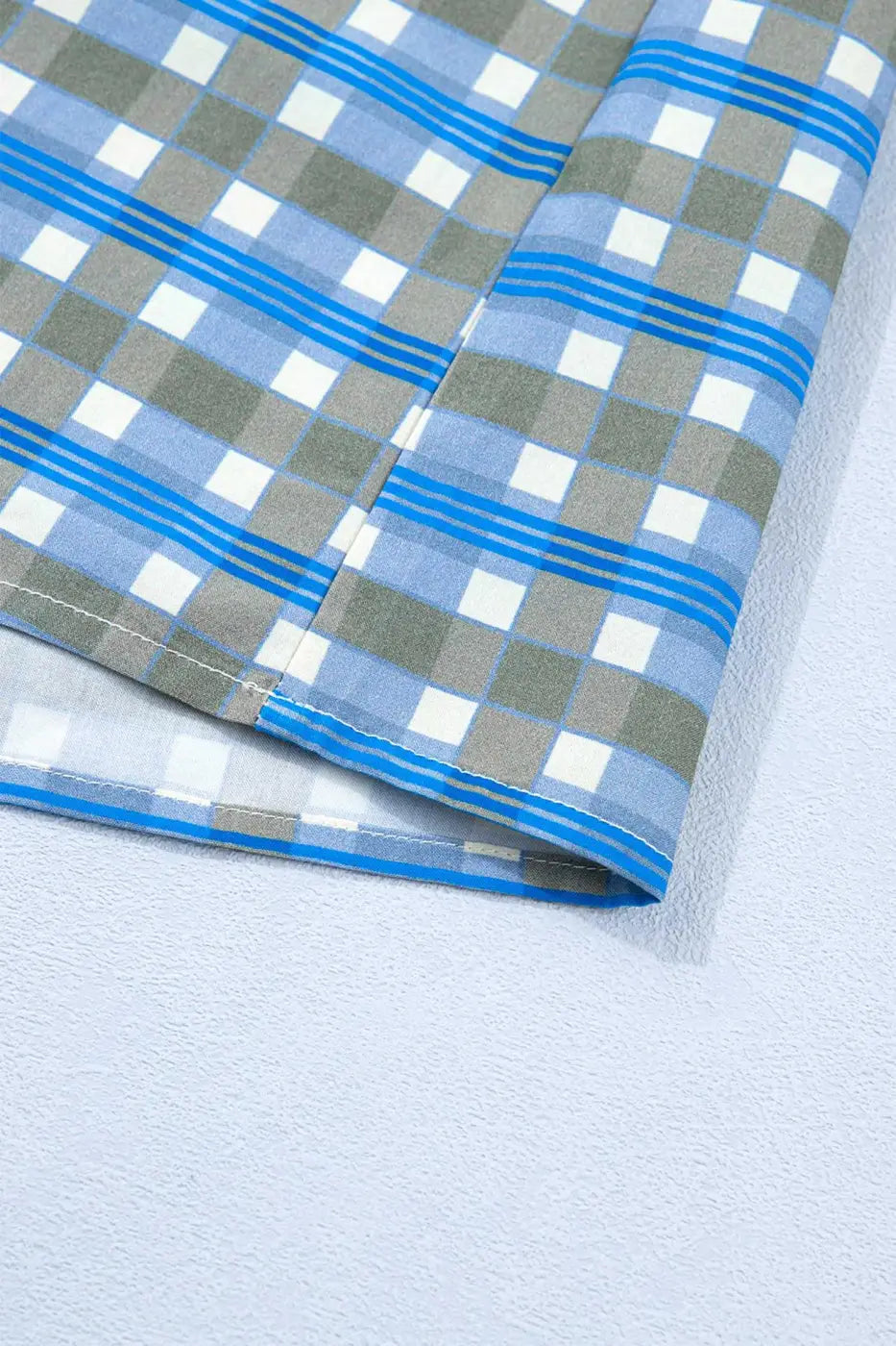 Hem detail of blue plaid long sleeve frilled blouse for women, made of breathable cotton with a relaxed fit and casual spring style.