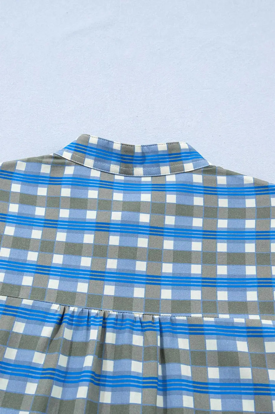 Back view of blue plaid frilled blouse with gathered yoke and breathable cotton texture, perfect for spring casual outfits.