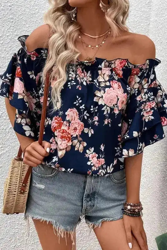 Blue floral off‑shoulder blouse with ruffle and flounce sleeves, paired with accessories and shorts for a trendy summer ensemble.