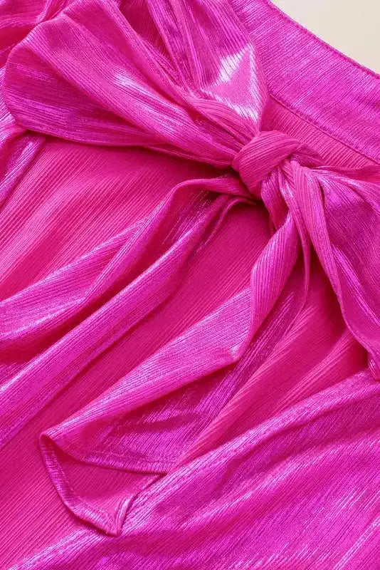 Detailed view of large satin bow on back of bright pink blouse, highlighting the elegant knotted design.