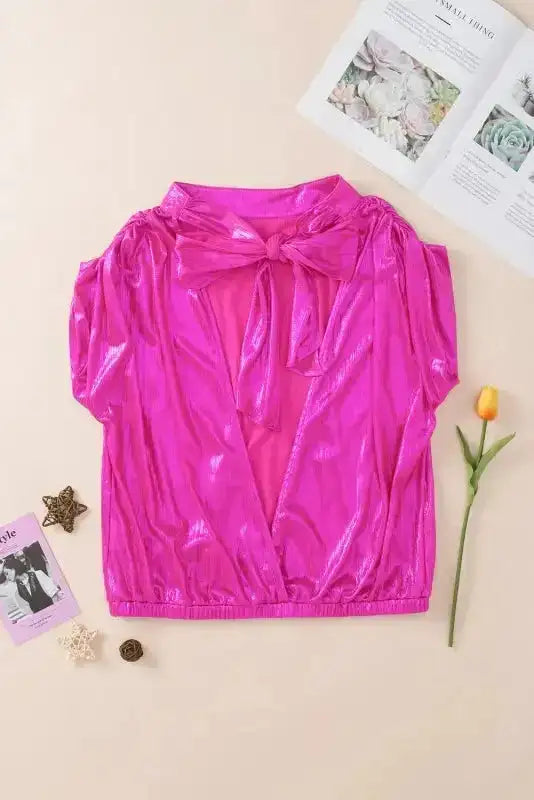 Flat lay of backless bright pink blouse with knotted bow detail, ideal for night out or summer party wear.