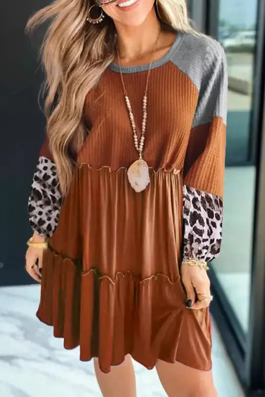 Waffle knit dress with leopard patchwork sleeves and tiered skirt accessorized with a pendant