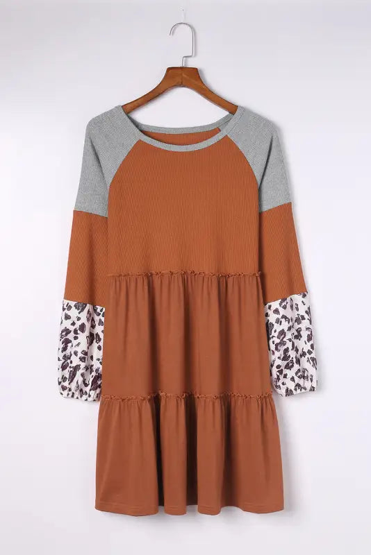 Brown waffle knit dress with leopard cuffs and gray sleeves on wooden hanger