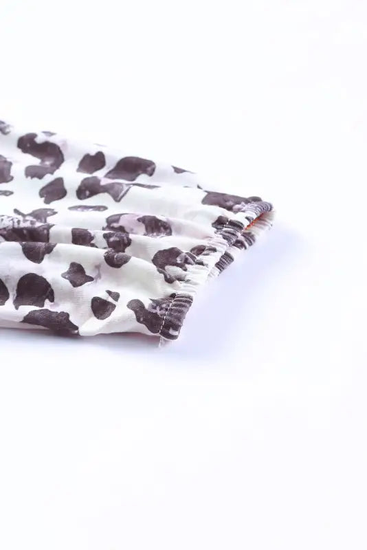 Folded fabric with black and white cow print on a brown waffle knit dress. Relax relax