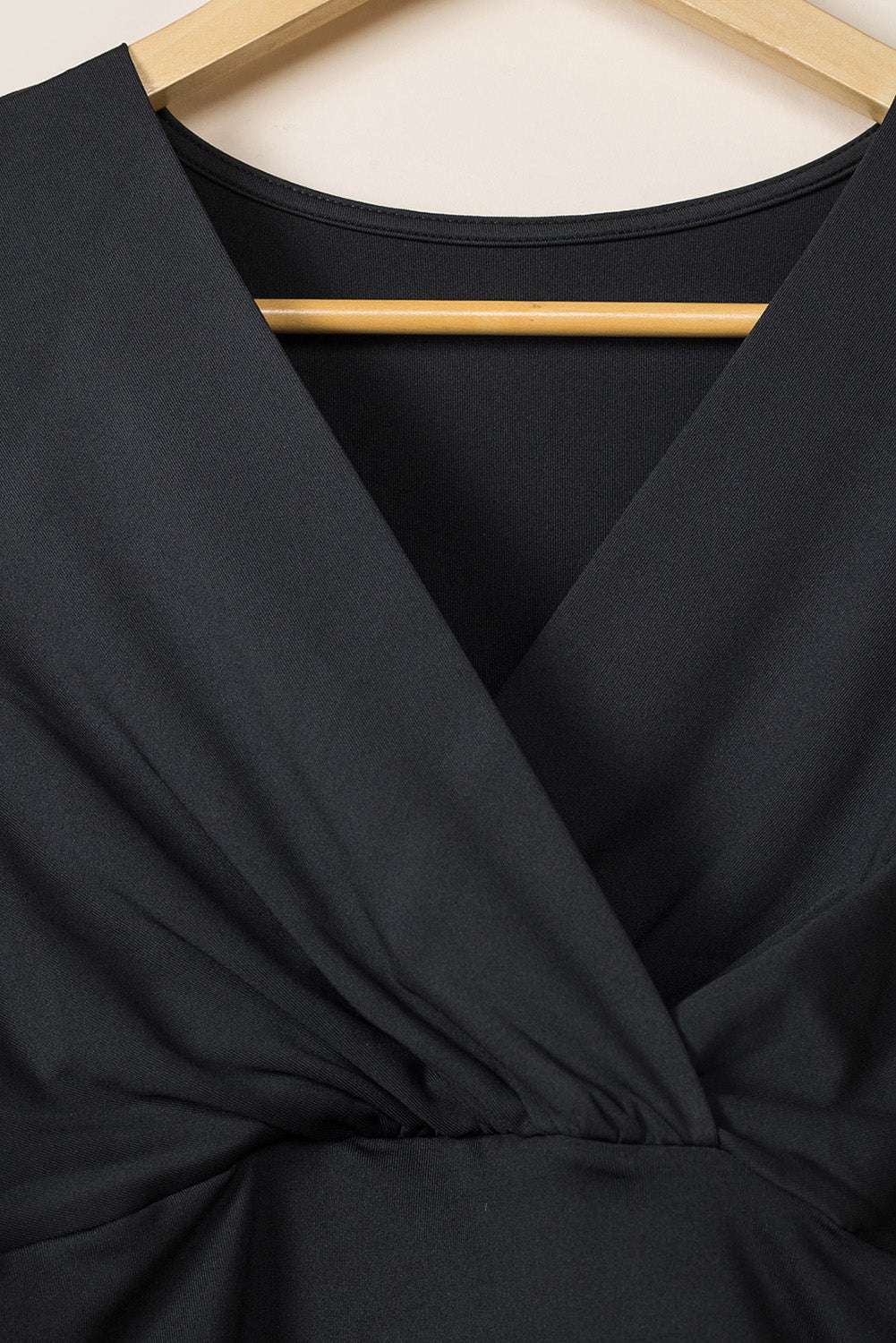 Detailed view of V-neck wrap bodice on Ladies Black Wrap Drape Midi Dress, emphasizing elegant neckline and draped fabric.
