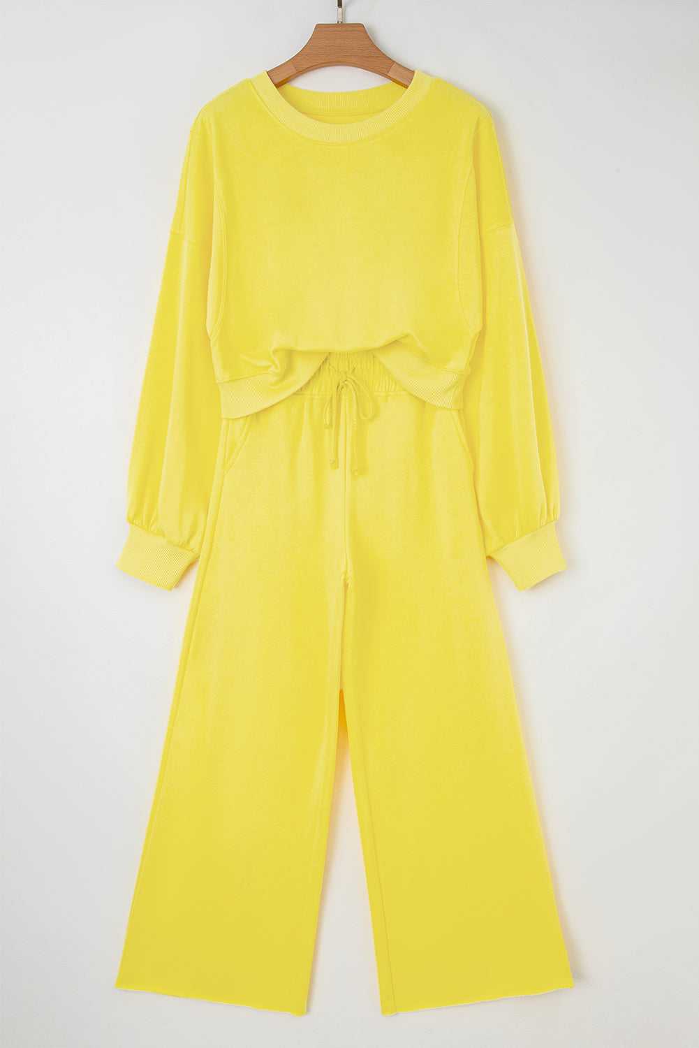 Flat lay of yellow Drop Crop Wide-Leg Pants Set on hanger, featuring cropped sweatshirt and wide-leg pants for casual wear.