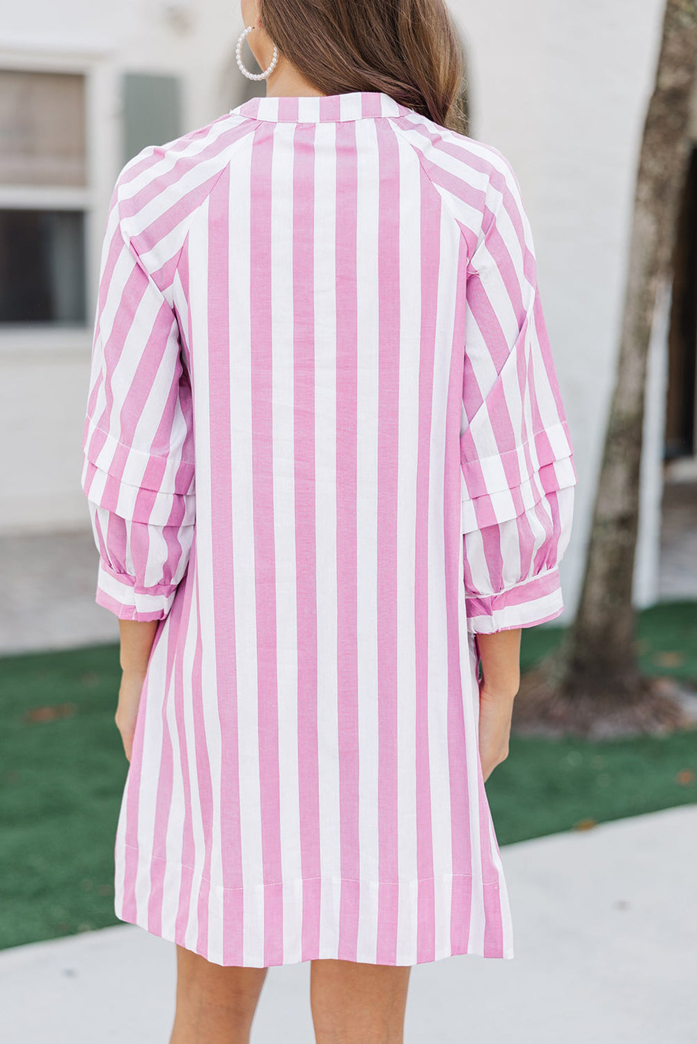 Person wearing a pink and white striped dress with a blurred background