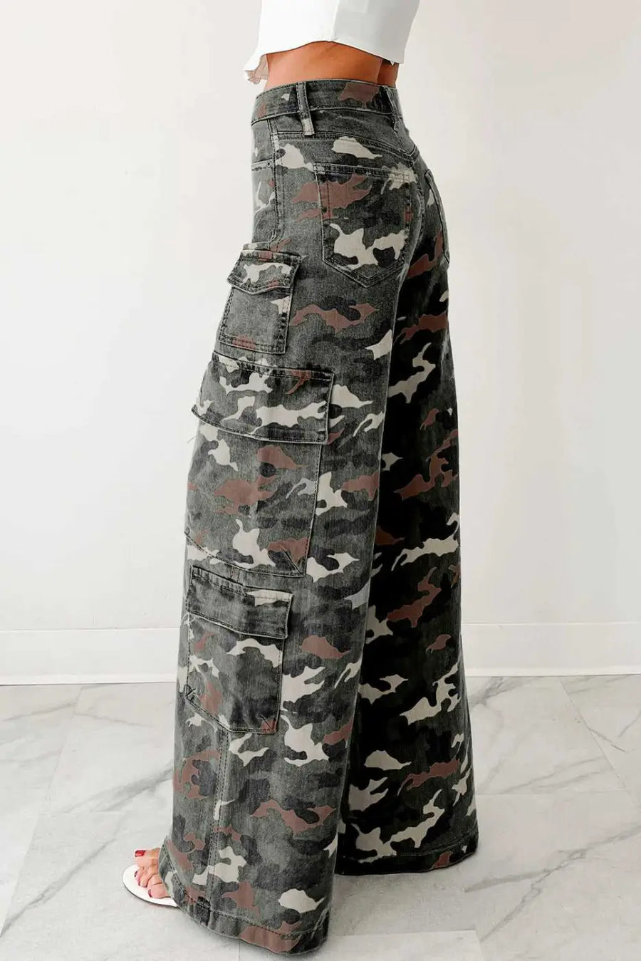 Side view of camo cargo jeans women with wide leg silhouette and multiple flap pockets. Green camo denim pants ideal for casual outfits.