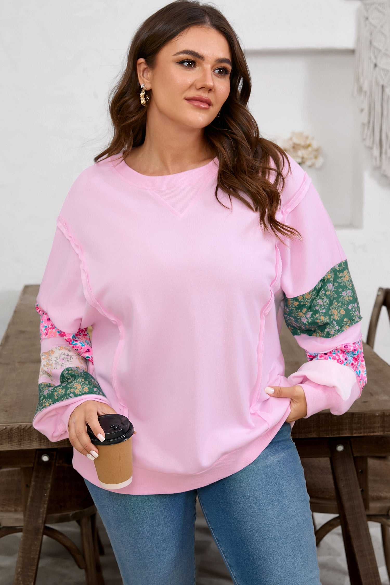 Plus size model wearing Curve Pink Floral Sleeve Baggy Sweatshirt for Women, styled with denim and holding a coffee cup for a cozy daily outfit.