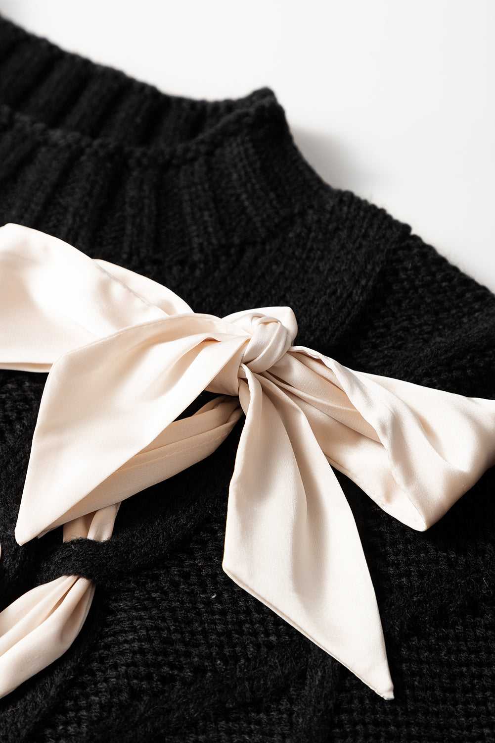 Close-up of the Satin Bowknot Sweater's neckline with a cream satin bow, highlighting the soft knit texture and delicate detailing.