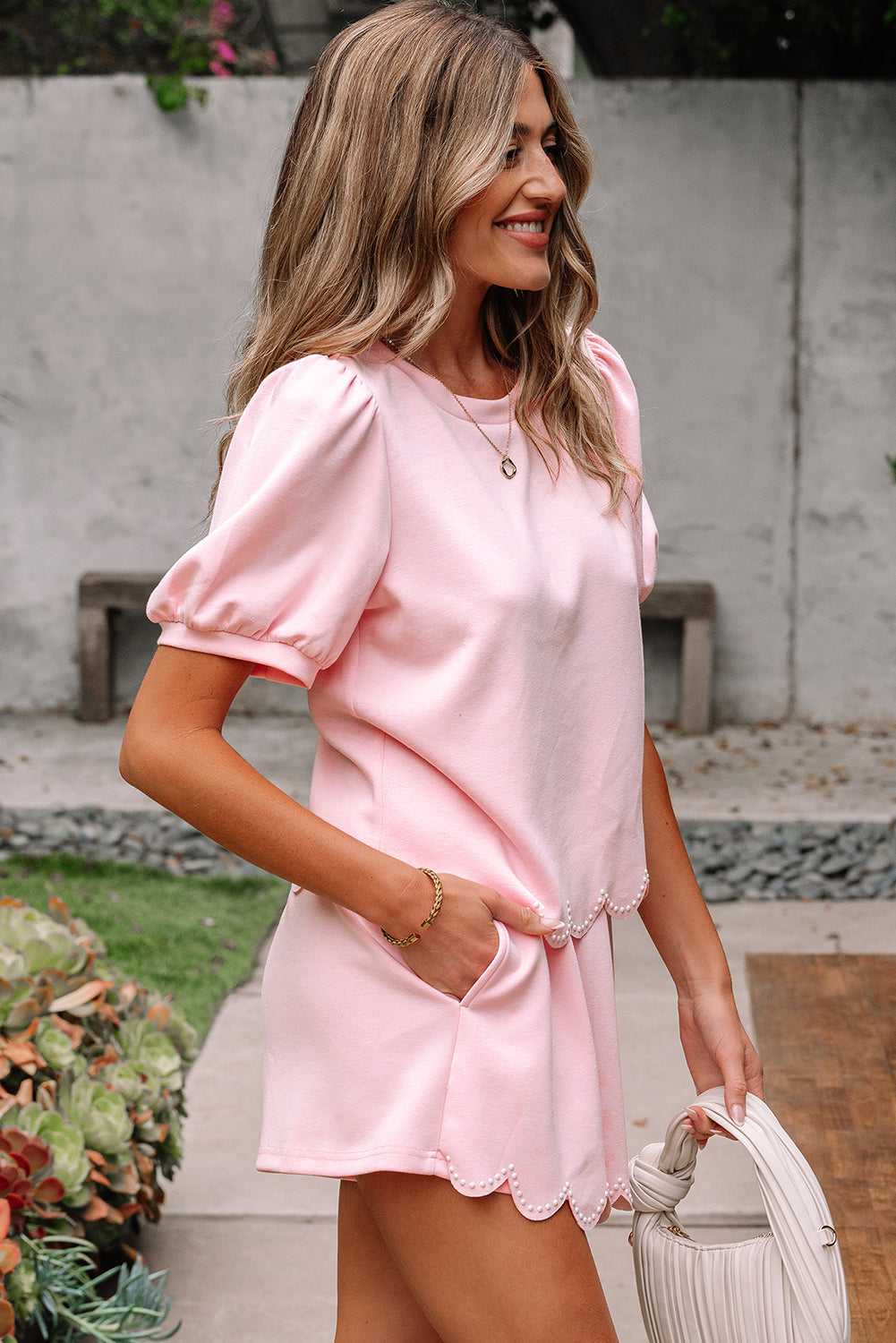 Woman wearing a pink skort set  standing outdoors with a neutral background