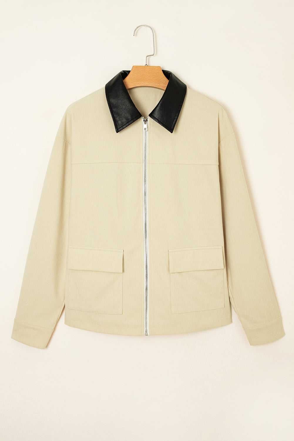 Beige jacket with black collar on a hanger against a beige background