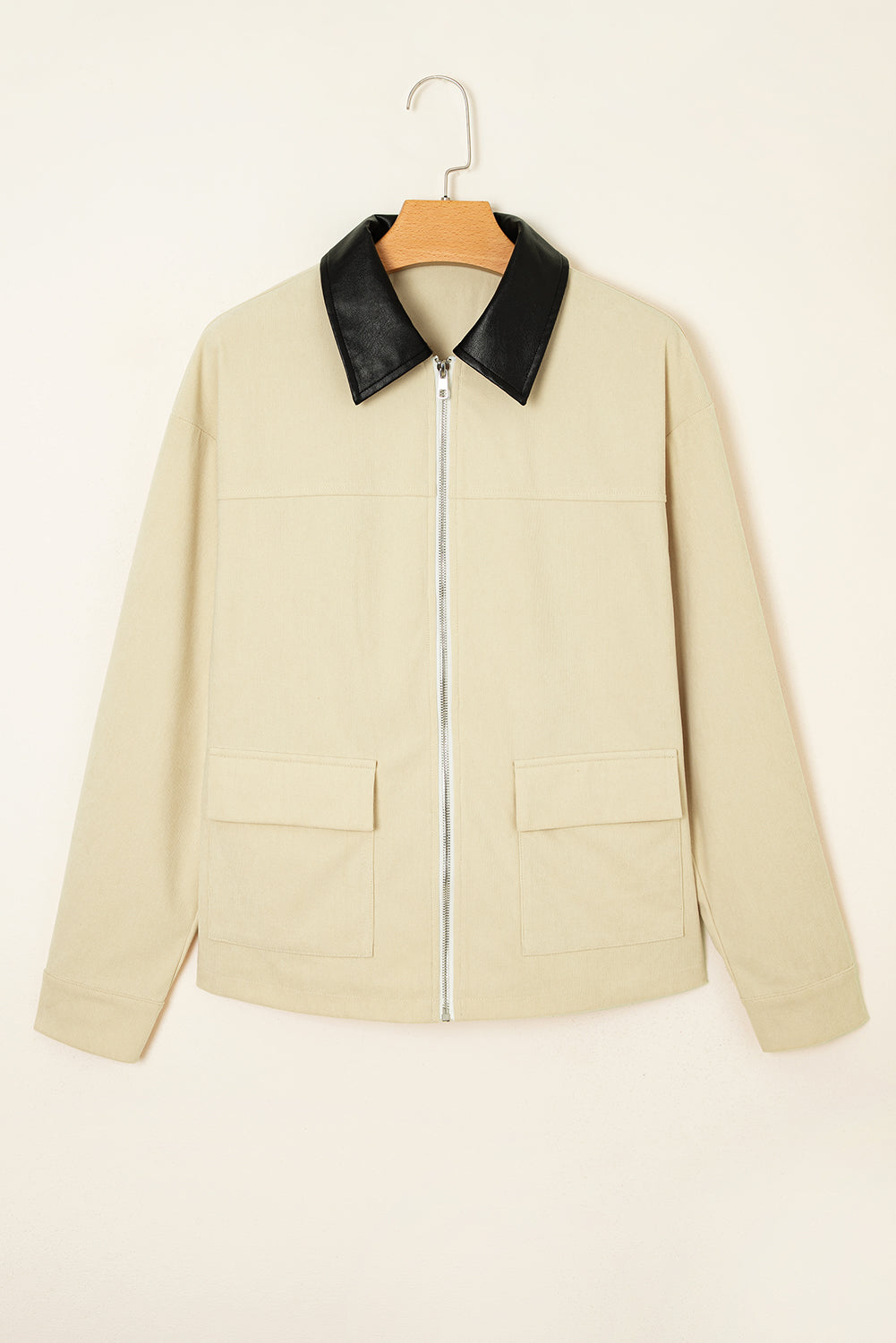 Beige jacket with black collar on a hanger against a beige background