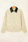 Beige jacket with black collar on a hanger against a beige background