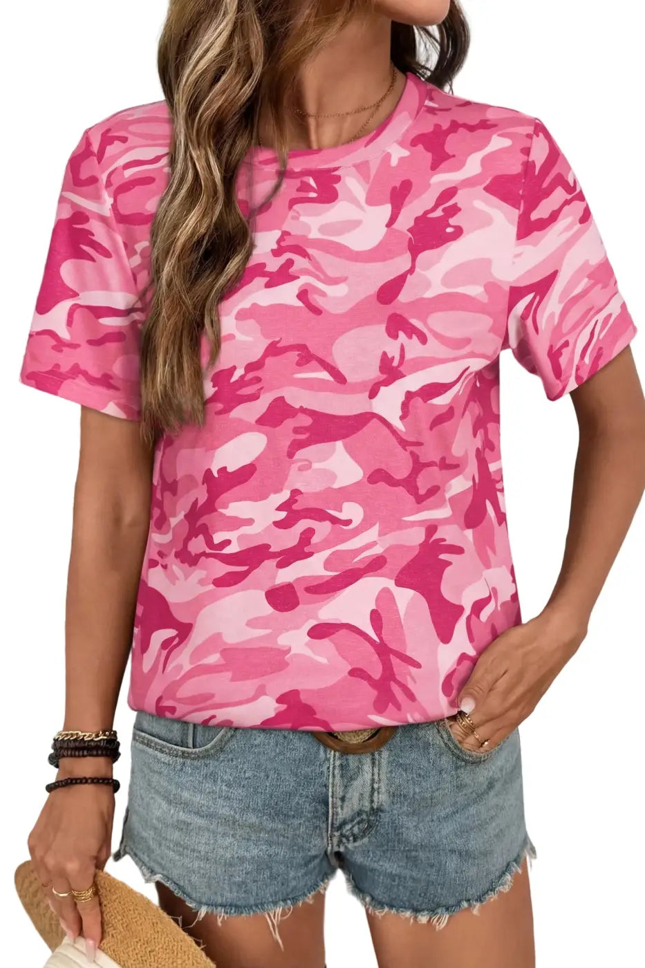 Person wearing a pink camouflage t-shirt and denim shorts against a white background