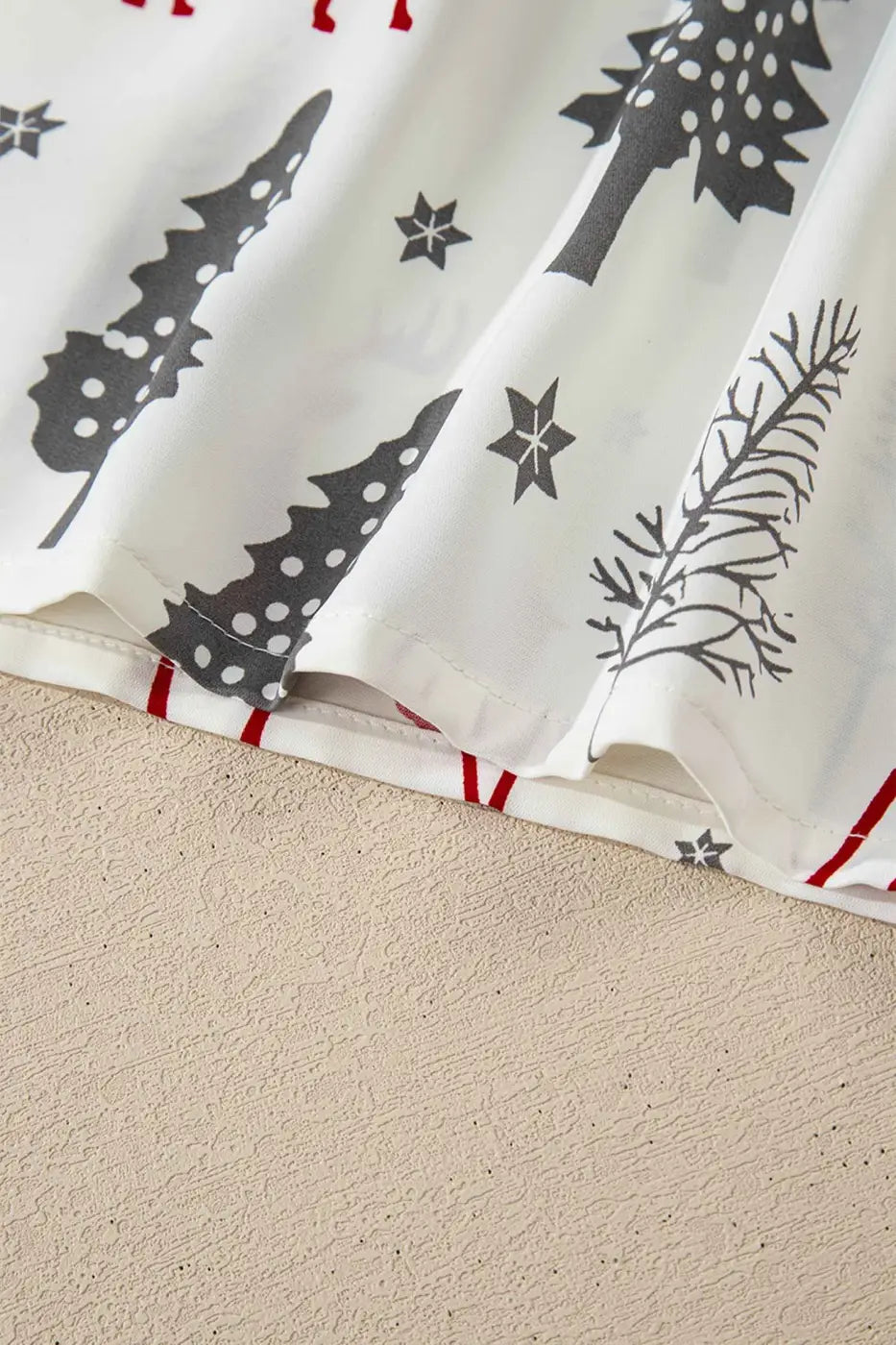 Close-up of hem on White Christmas Print Velvet Trim Pyjamas showing festive tree and star patterns, perfect for cozy holiday sleepwear.