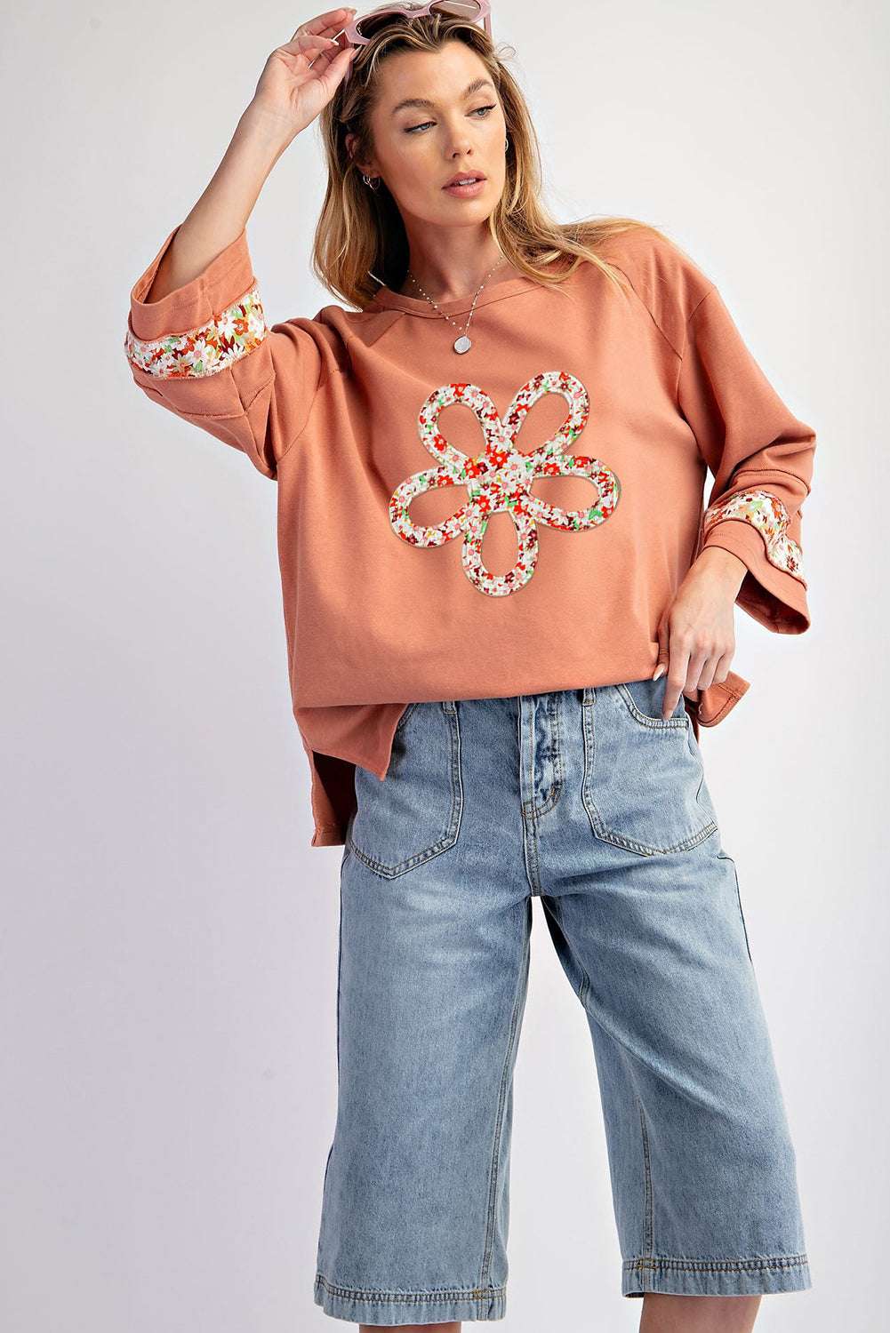 Model wearing Flower Patch Graphic Top with floral applique and wide sleeves, paired with denim bermuda shorts for a Southern Belle style.