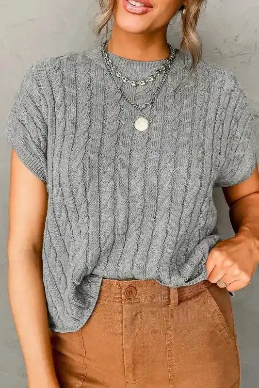 Gray Cable Knit Sweater - Short Sleeve Style with ribbed hem and crew neck, styled with brown pants for a neutral, casual look.