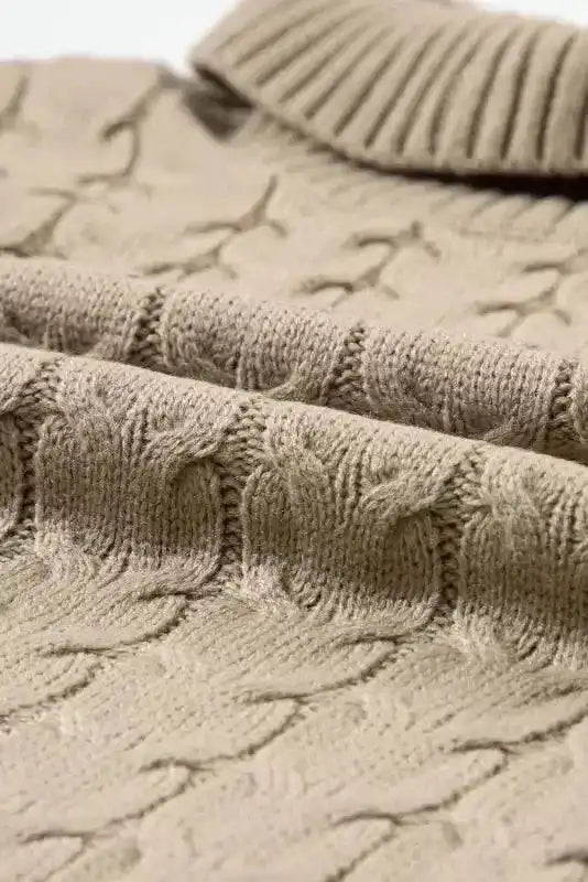 Close-up of beige cable knit texture and ribbed collar. Wrinkle-resistant acrylic fabric ideal for autumn and winter layering.