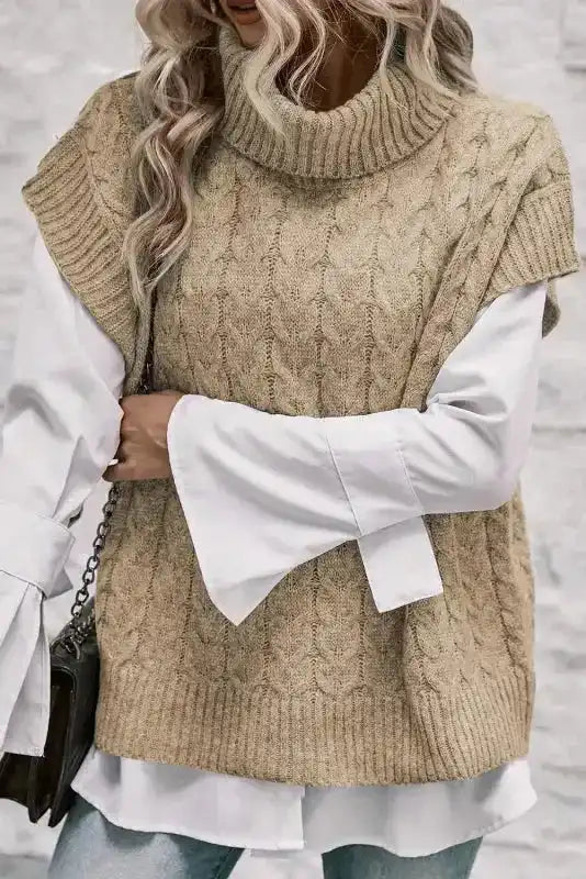 Beige cable knit turtleneck jumper layered over a white blouse. A fashionable and cozy autumn top for women’s smart casual looks.