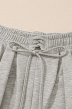 Close-up of gray pleated sweatpants waistband with drawstring and pleat detailing, highlighting comfort and design.