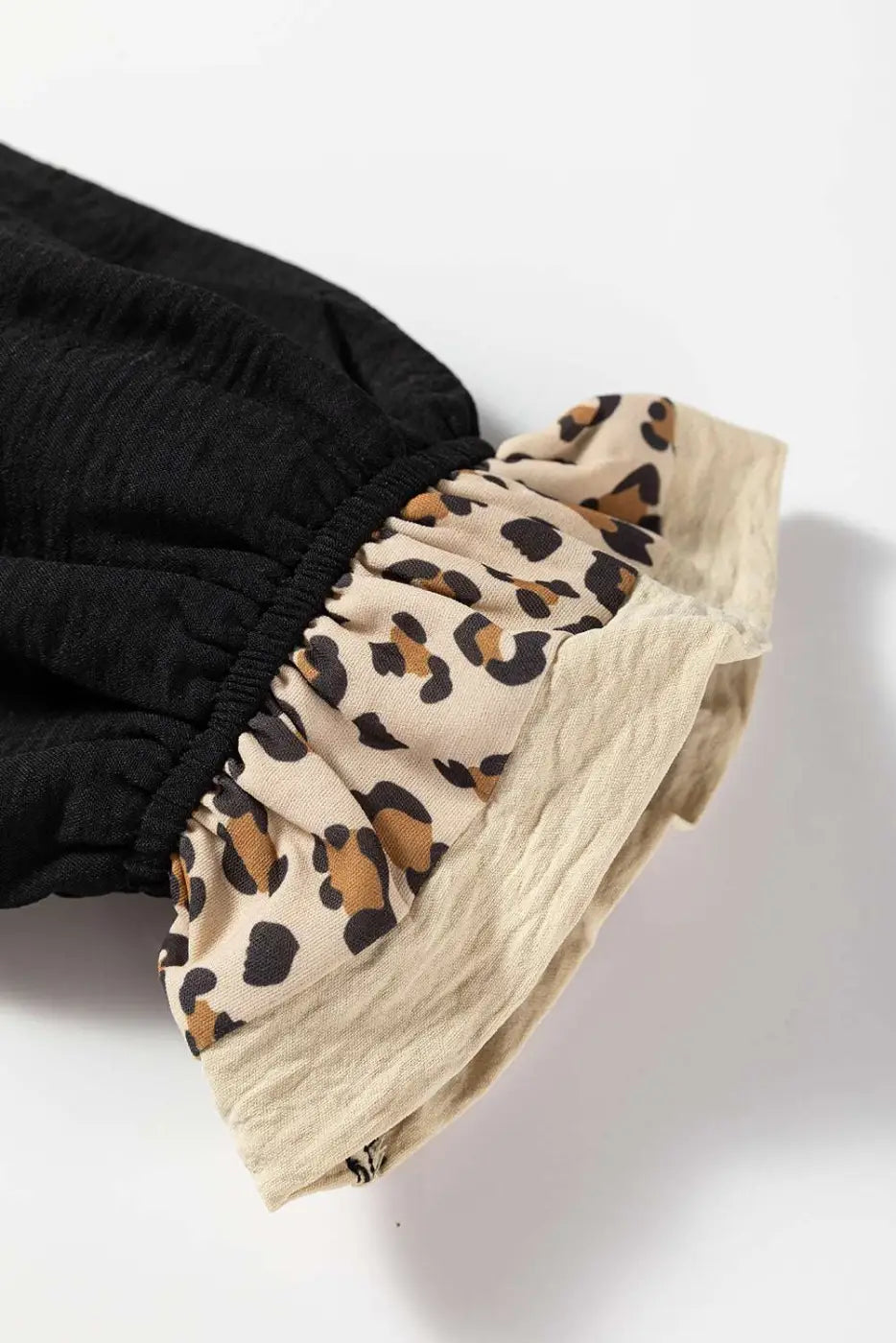 Detailed close-up of ruffled leopard print sleeve cuff on Black Camel Leopard Fusion Polo Blouse, showcasing layered fabric texture.