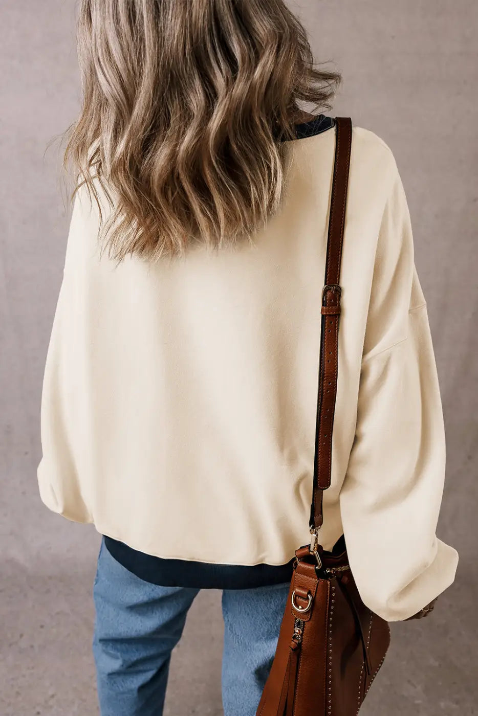 Casual oversized sweatshirt: cream sweater with blue jeans and brown leather shoulder bag