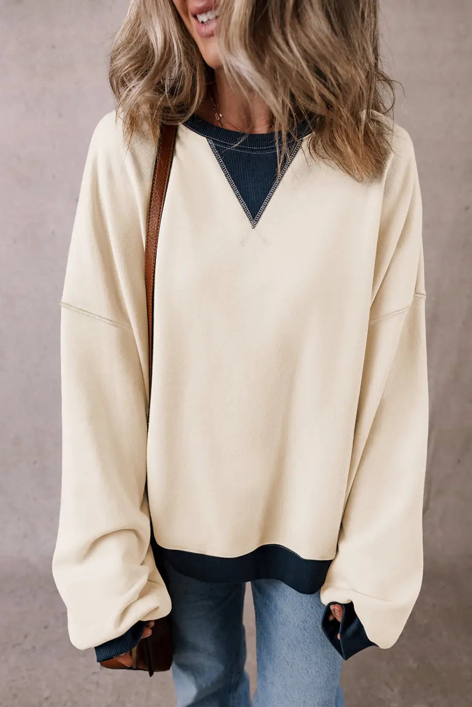 Cream-colored casual oversized sweatshirt with navy blue v-neck insert and cuffs