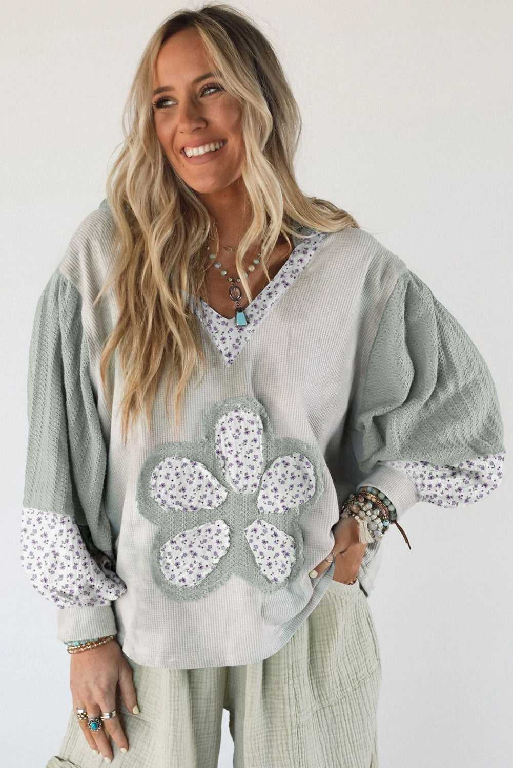 Woman wearing a light gray hoodie with floral patterns on a white background