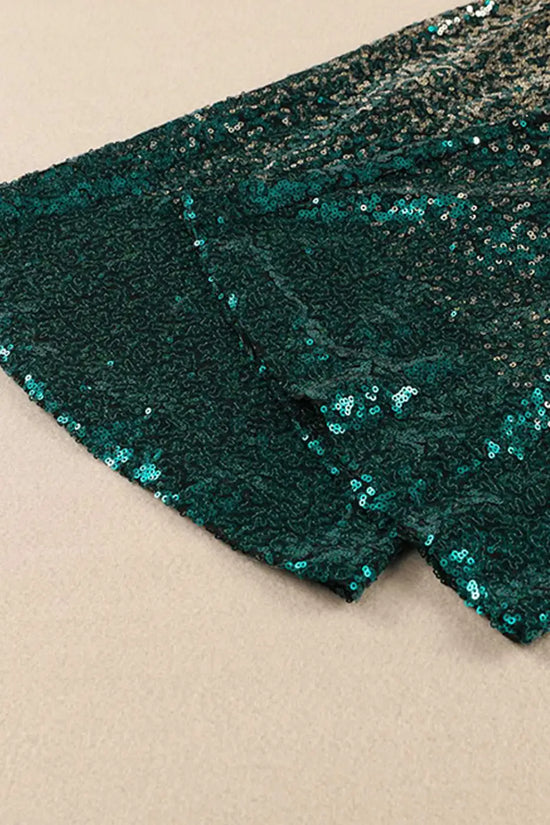 Close-up of flared hem on green and gold sequin trousers. Detailed view of shimmering sequin texture and elegant flare.