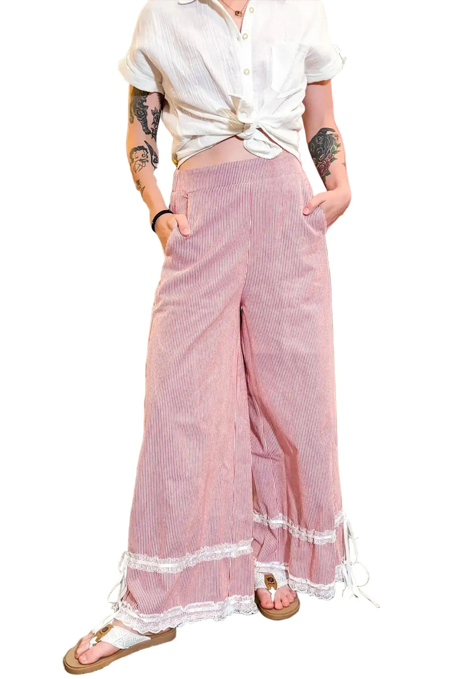 Person wearing a white blouse and pink pants with lace trim in a store setting