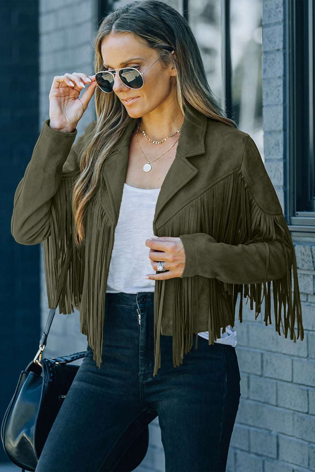 Fashionable green cropped fringe faux suede jacket with layered necklaces and sunglasses, ideal for autumn street style.