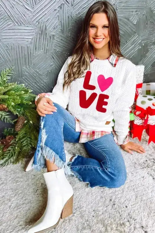 Valentine's Day themed 'LOVE' sweatshirt with chenille embroidery, styled with jeans and boots for casual romantic look.