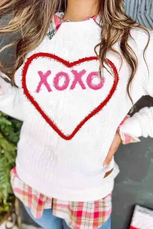 Close-up of heart-shaped 'XOXO' chenille embroidery on white sweatshirt, ideal for romantic seasonal apparel.