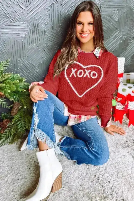 Model wearing red 'XOXO' heart sweatshirt with jeans and boots, perfect for festive Valentine's fashion.