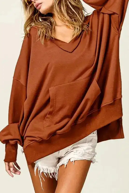 Chestnut oversized hoodie with V-neck and kangaroo pocket styled with white distressed shorts, ideal for casual autumn wear.