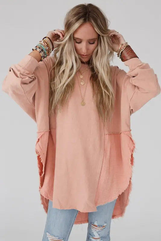 Woman in chic high-low hem oversized blouse with exposed seam, layered jewelry