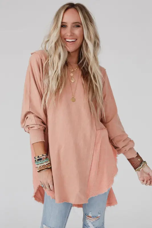 Smiling woman in chic high-low hem oversized blouse with exposed seam design