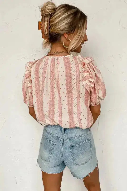 Back view of Chic Peek Puff Sleeve Blouse featuring ruffle details and vertical polka dot stripes, paired with light denim shorts.