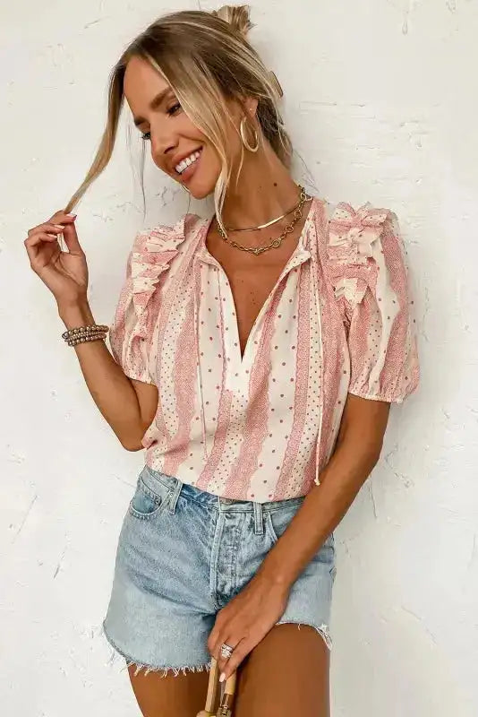 Chic Peek Blouse styled with denim shorts, featuring puff sleeves, tie neck, and a pink polka dot and stripe print for summer.