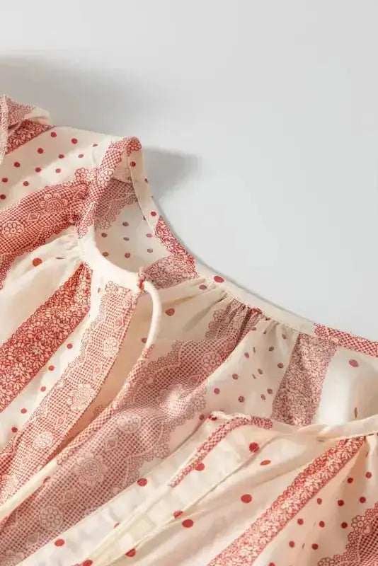 Neckline detail of Chic Peek Blouse with tie closure and soft gathers, featuring pink polka dot and stripe print.
